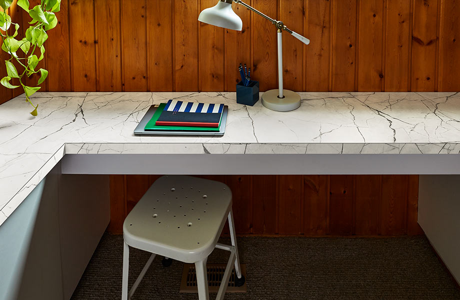 White marble laminate corner desk with notebooks, lamp and metal stool