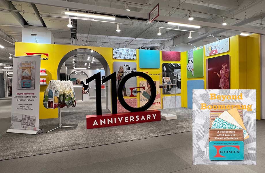 A large black and red ‘110 Anniversary’ 3D floor sign surrounded by historic Formica Brand ads and colors inside a booth with an image in the corner of the ‘Beyond Boomerang’ book 