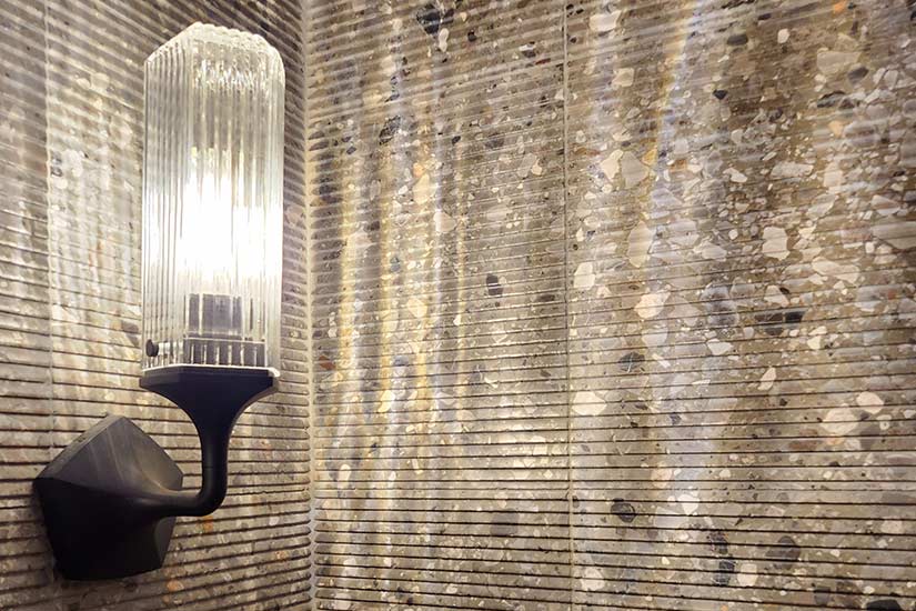 Close-up of ribbed stone wall with light sconce