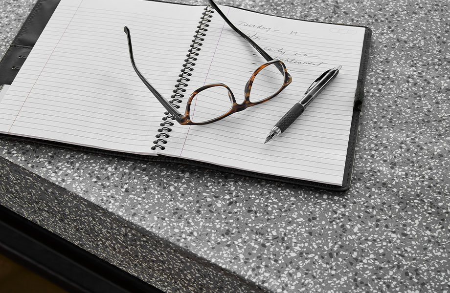 411 Grafite Terrazzo Matrix solid surface countertops with notebook and glasses