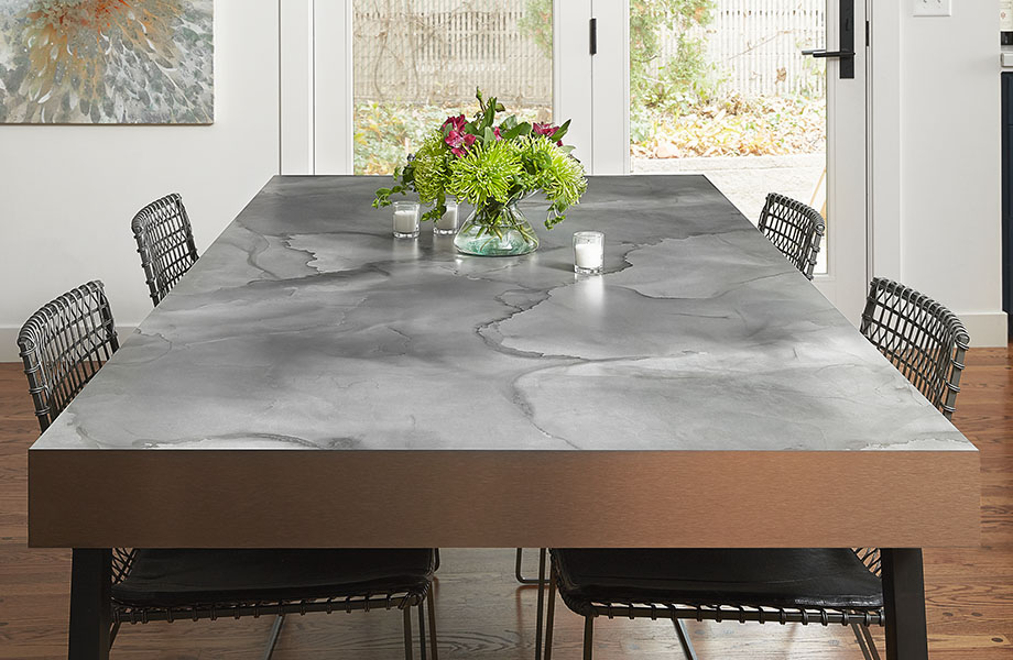 Dining room table surface made with Formica® HPL laminate 180fx® 5017-11 Watercolor Steel – a blend of warm and cool grays with hints of blue and charcoal black as seen in tempered steel, a perfect pattern for the moody and inky tones in interiors today.