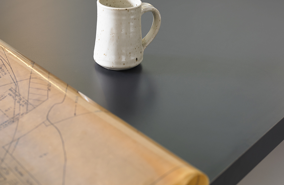 Close-up of 5323-AN Nocturne black tabletop with mug and blueprints