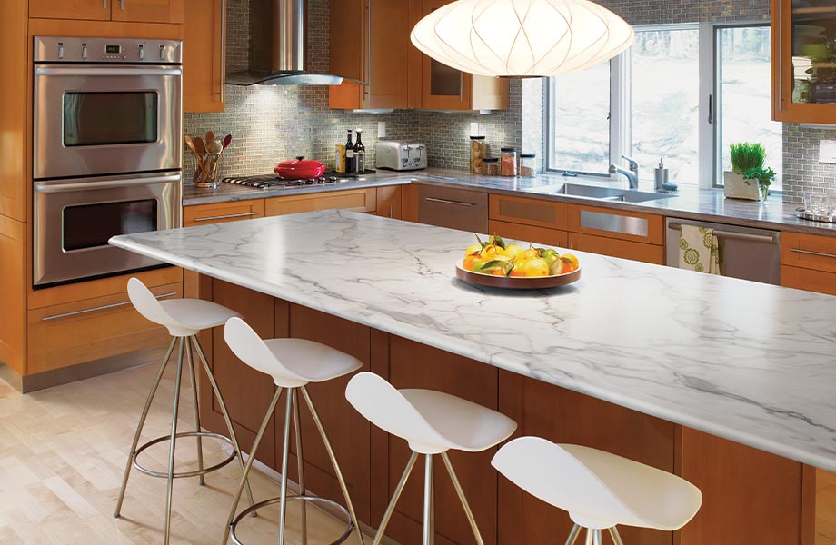 A modern home kitchen with an island in the foreground, featuring 3460 Calacatta Marble 180fx Laminate by Formica Grou
