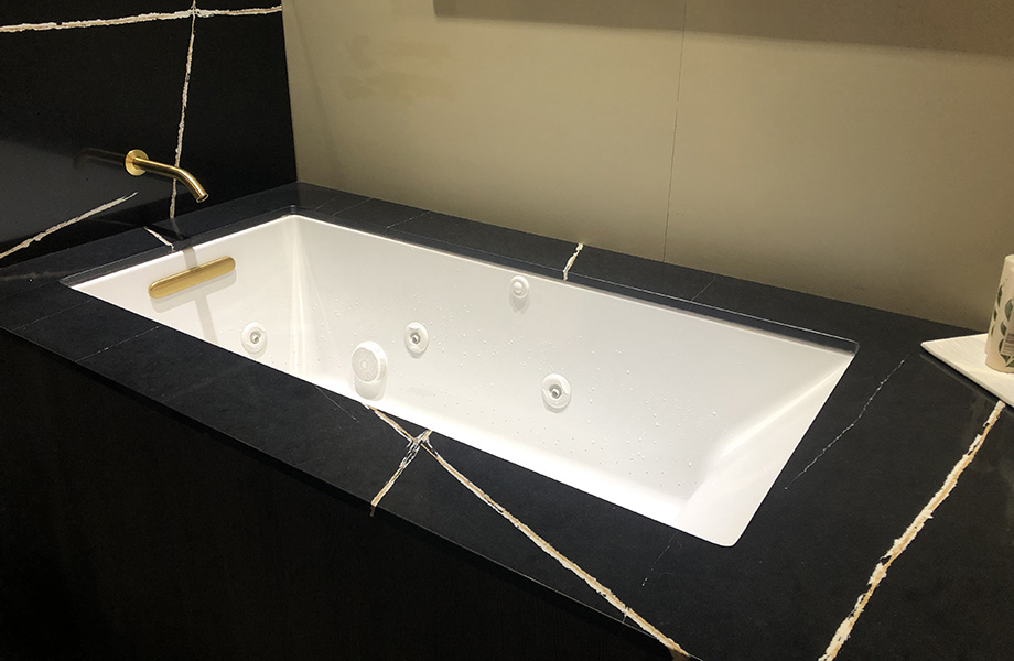 Kohler’s black marble stone bathtub surround with white tub
