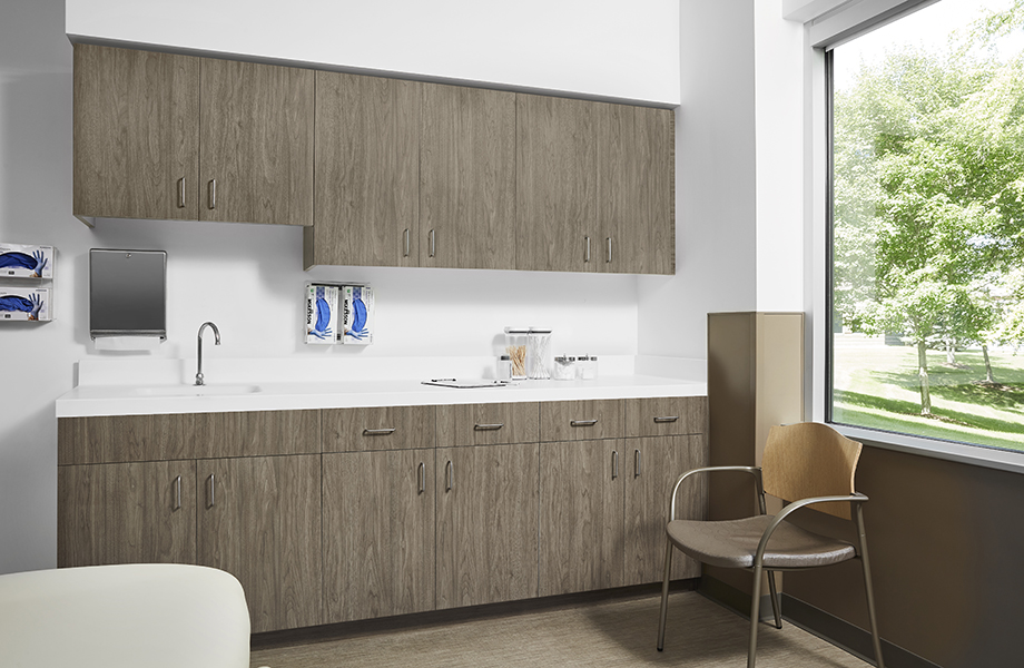 Patient room with chair, 5788-NG Hazel Walnut cabinetry and 408 Luna Brite White acrylic solid surface countertops