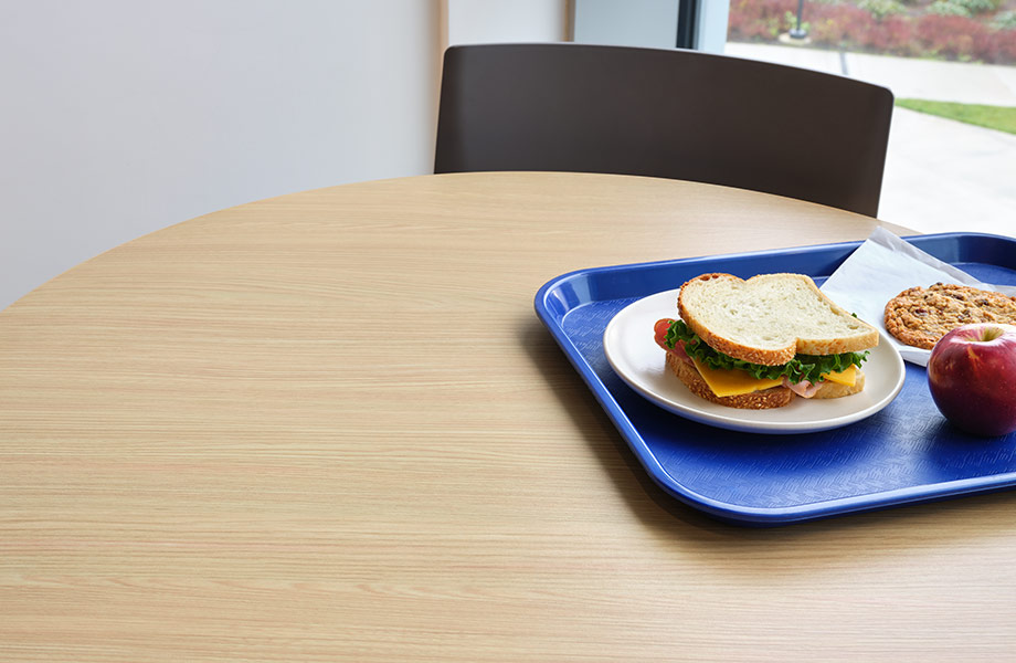 Light woodgrain laminate tabletop with lunch tray and chair