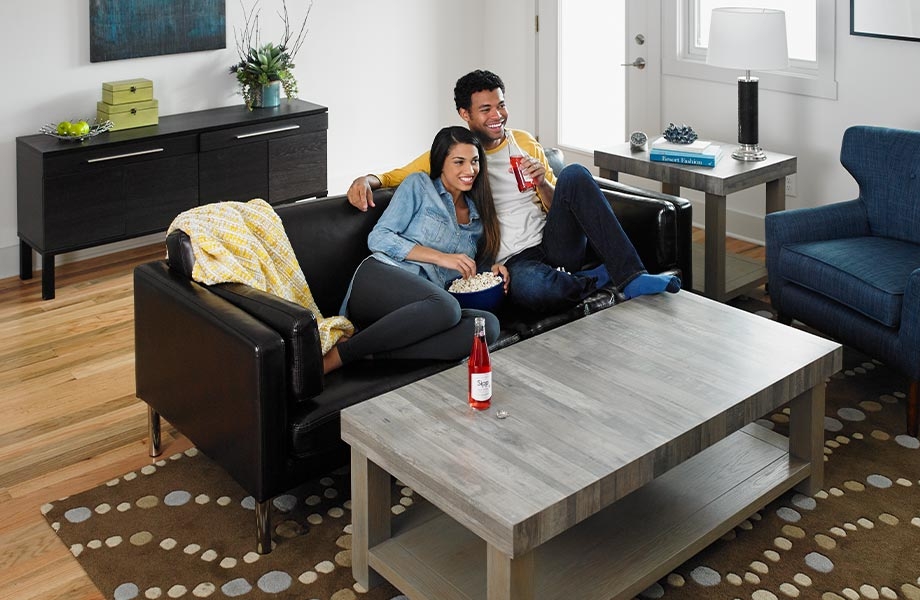 Hombre y mujer en el sofá de la sala con mesa de centro hecha de Laminado Formica Seasoned Planked Elm