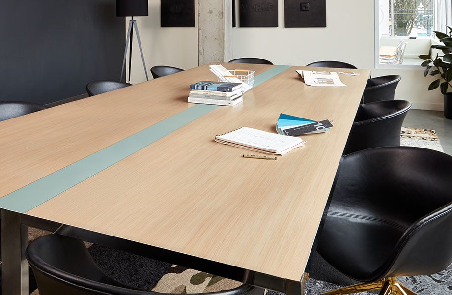 Mesa de sala de conferencias en oficina con Laminados Formica Wood Brushstroke y Fossil rodeada por sillas negras. 