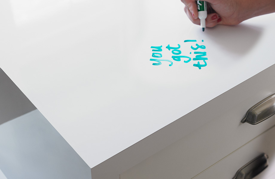 Une personne qui écrit sur un bureau en tableau blanc conçu avec le Stratifié de marque Formica 949 Blanc