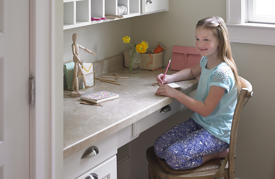 Fille assise à un bureau fabriqué avec du stratifié Formica® Travertin (3526)