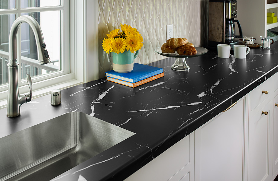 Cuisine moderne avec comptoir en stratifié noir et blanc (180fx® Nero Marquina, 7403-11). Évier et accessoires de café agencés aux armoires blanches